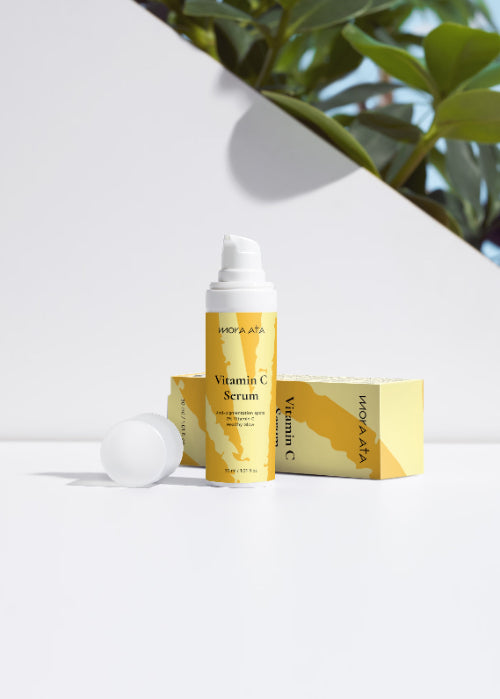 MORA ATA Vitamin C serum with packaging on a white surface with greenery in the background