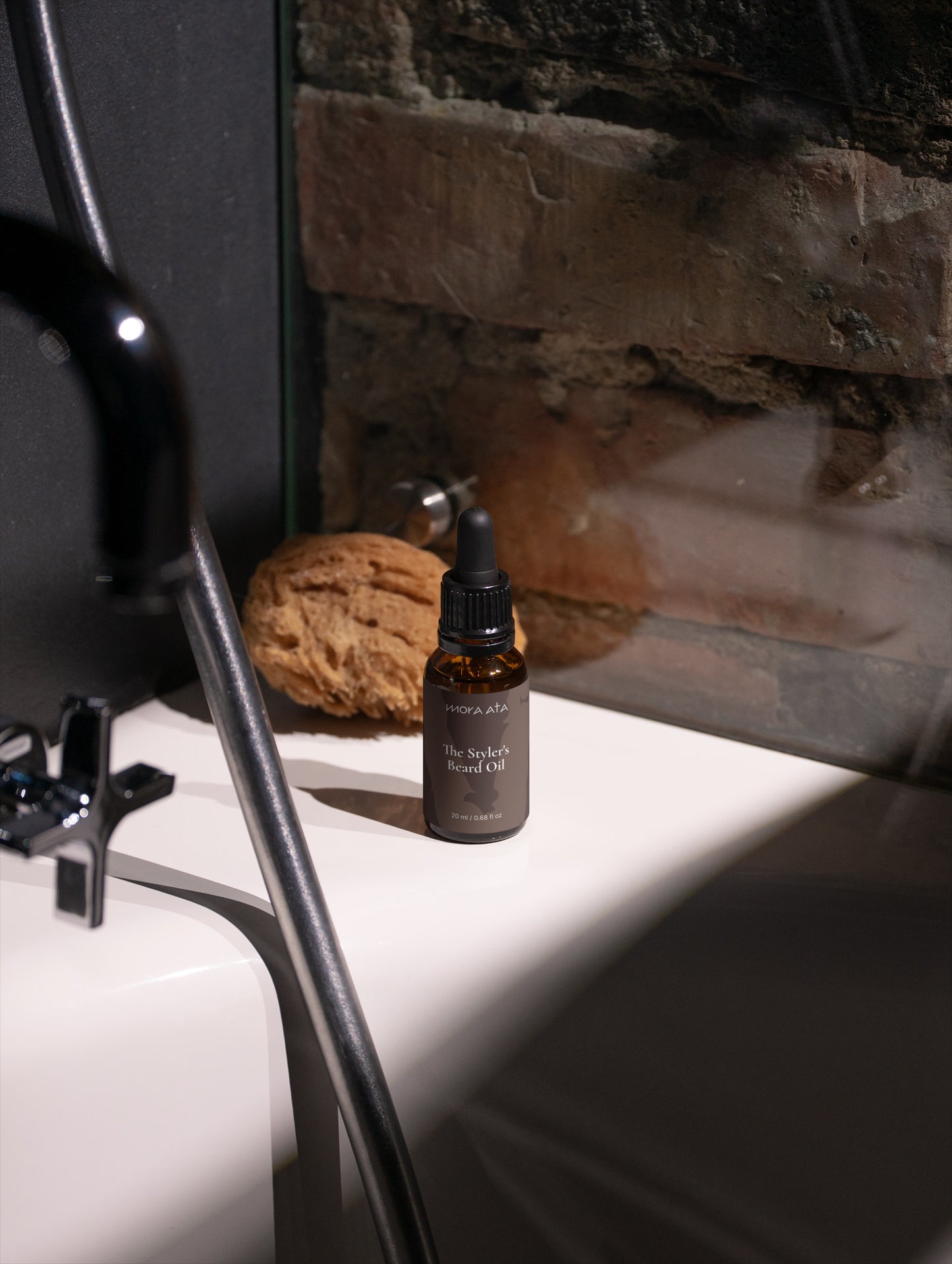 Mora Ata The Styler's Beard Oil bottle  on a white surface with a stone wall background